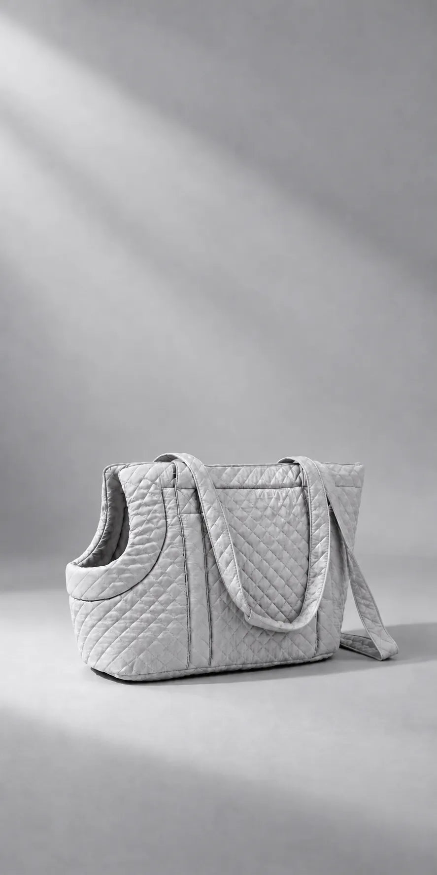 A grey diamond-quilted pet carrier photographed in a clean studio with directional light